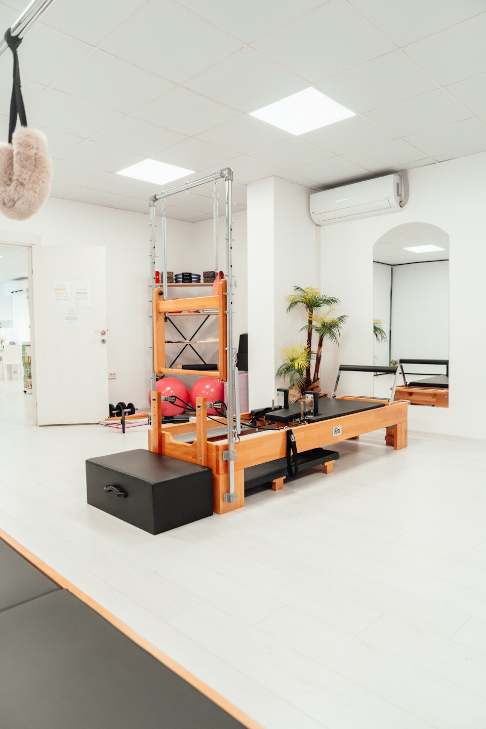 Pilates reformer machine sits in a bright exercise studio.
